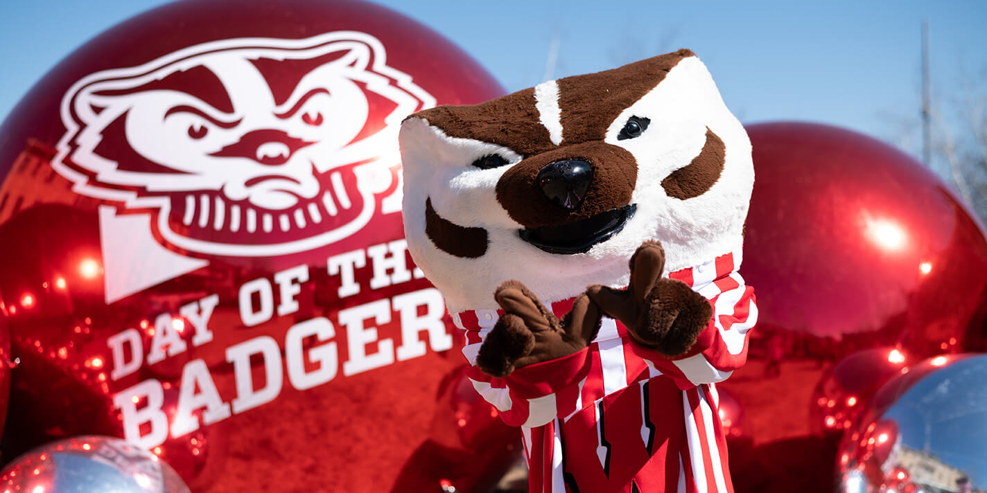 Bucky holding a "W" in front of a Day of the Badger shiny ball