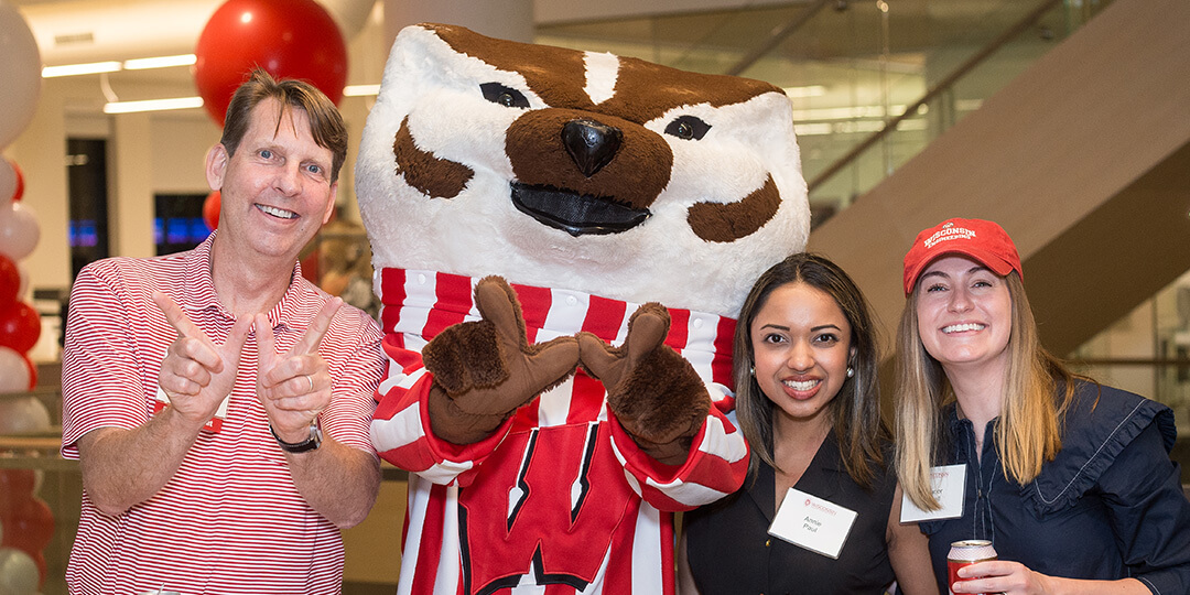 Bucky throws a "W" surrounded by three Twin Cities alumni.